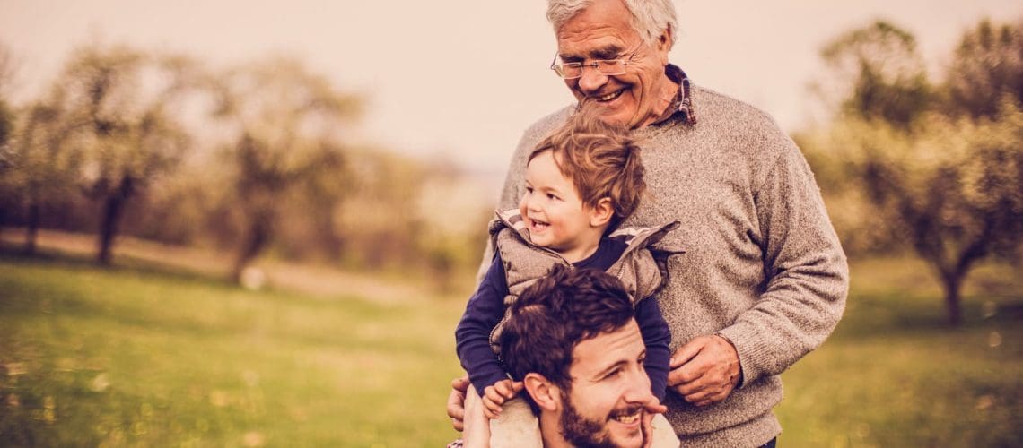 Photo of smiling little boy with his father and grandfather, enjoying in the amazing nature